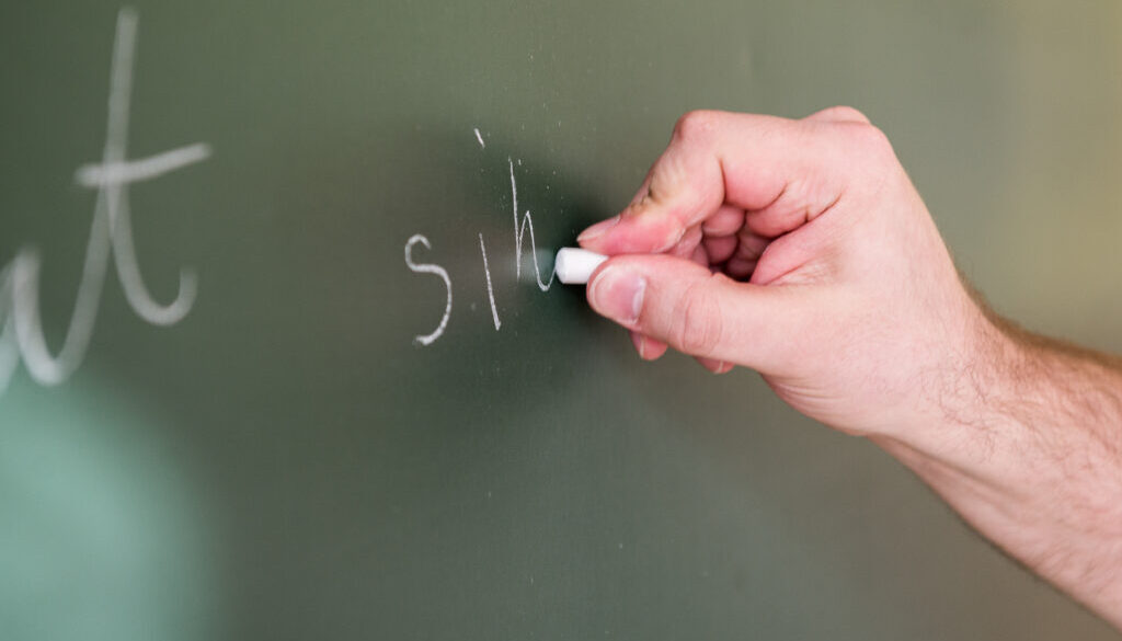 Nauczyciel piszący kredą na tablicy