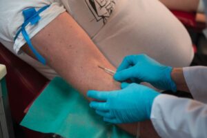Pielęgniarka w niebieskich rękawiczkach pobiera krew