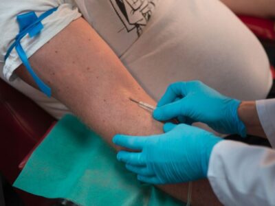 Pielęgniarka w niebieskich rękawiczkach pobiera krew