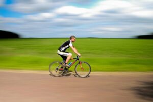 Mężczyzna na rowerze przejeżdża przez tereny wiejskie i zielone pola