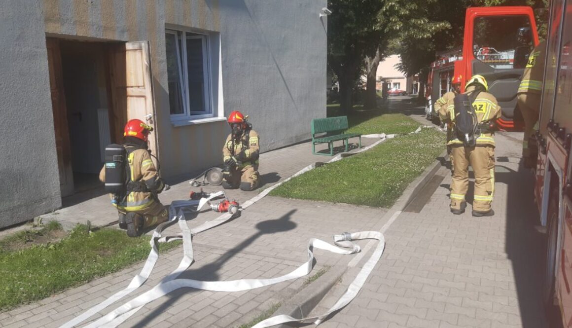 Strażacy rozkładają węże strażackie w trakcie ćwiczeń z gaszenia pożaru w chełmińskim szpitalu
