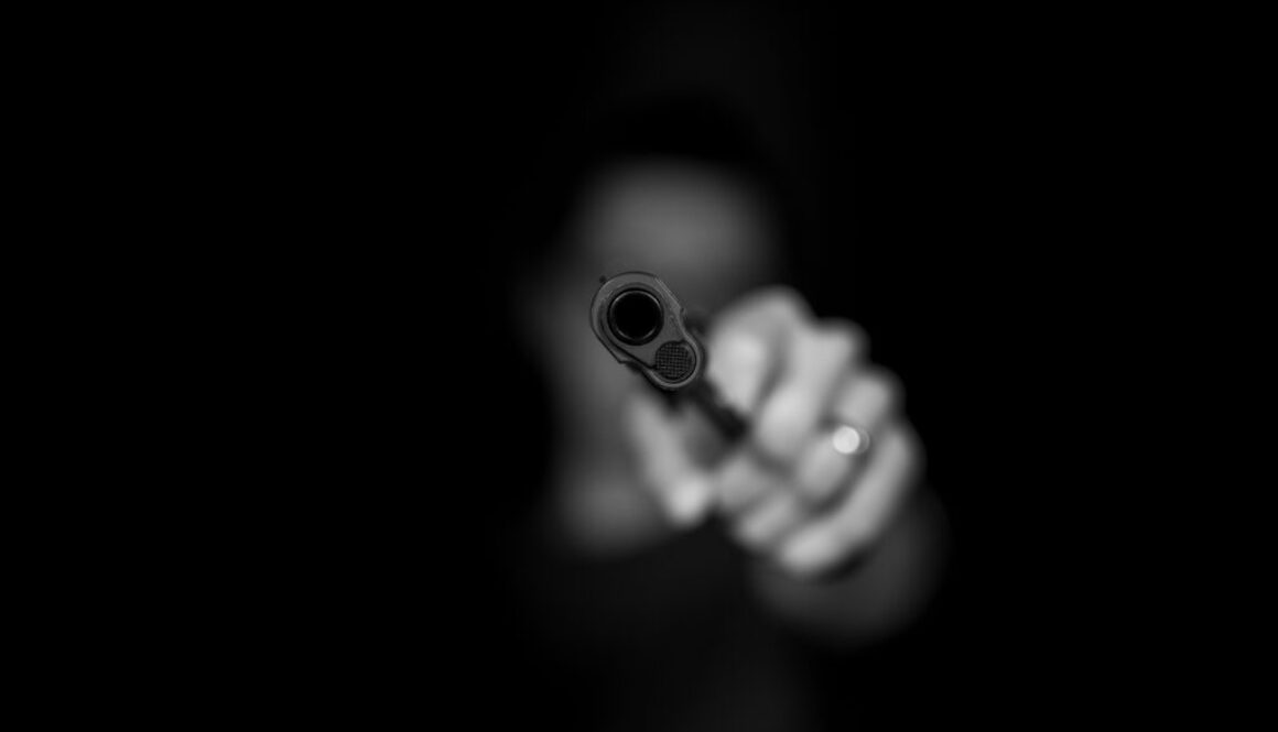 Mężczyzna trzymający pistolet na czarnym tle
