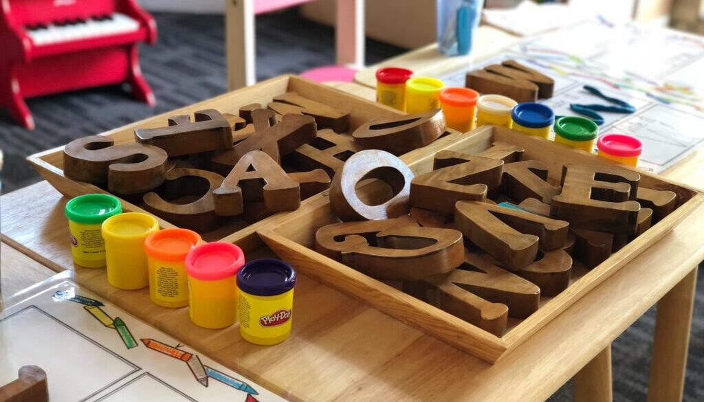 Drewniane literki i farby na stoliku w przedszkolu
