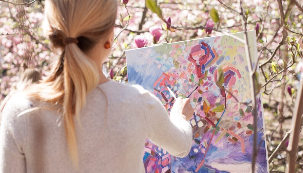 Blondynka maluje fioletowo-różowy obraz