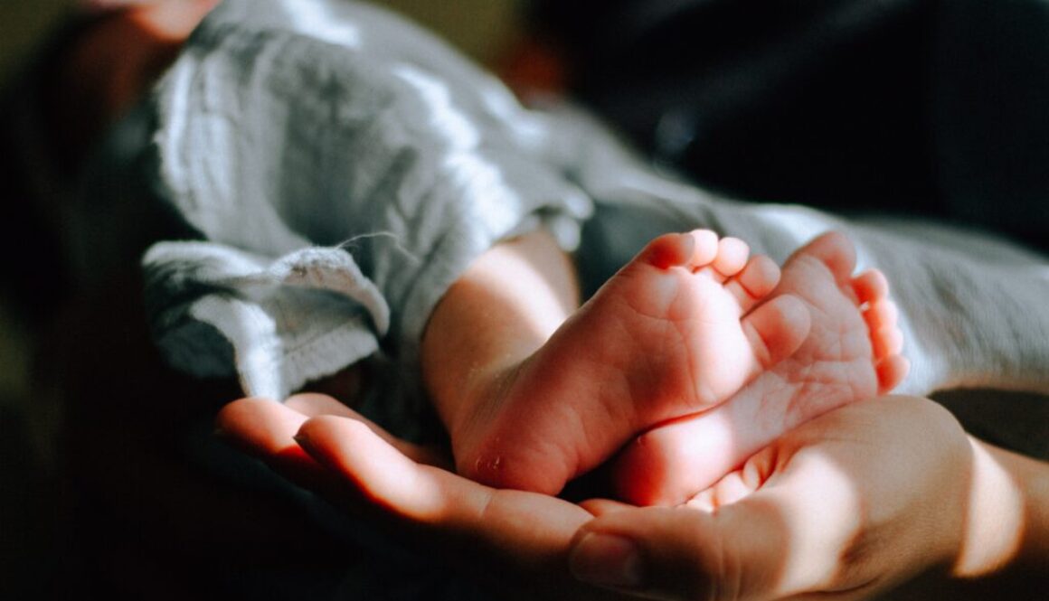 Stopy niemowlaka, podtrzymywane przez dłonie rodzica