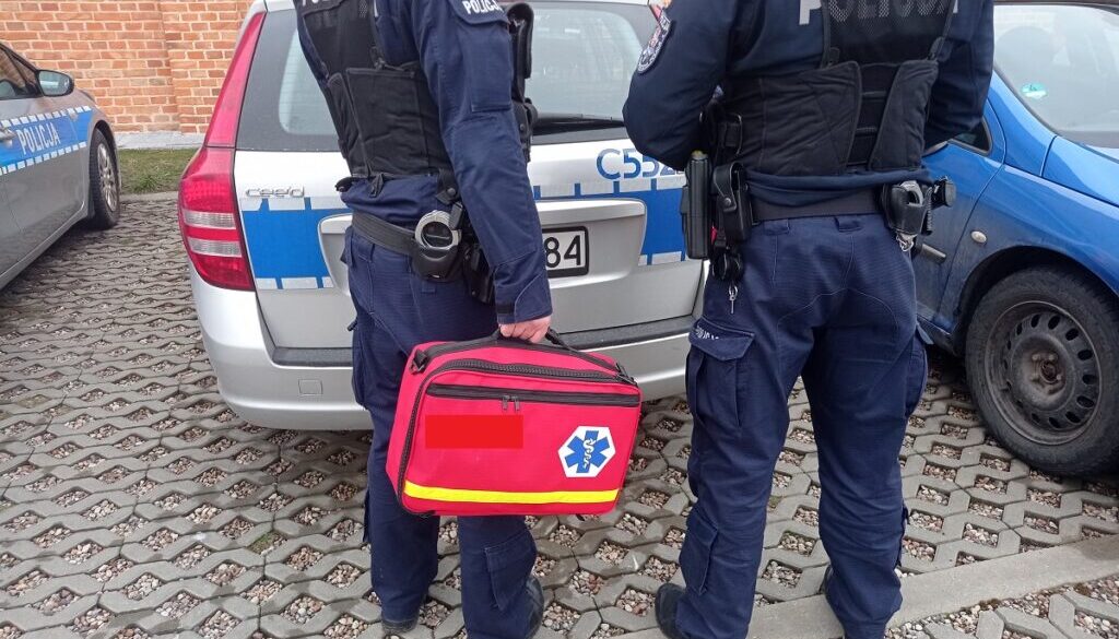 Policjanci z torbą medyczną przed radiowozem