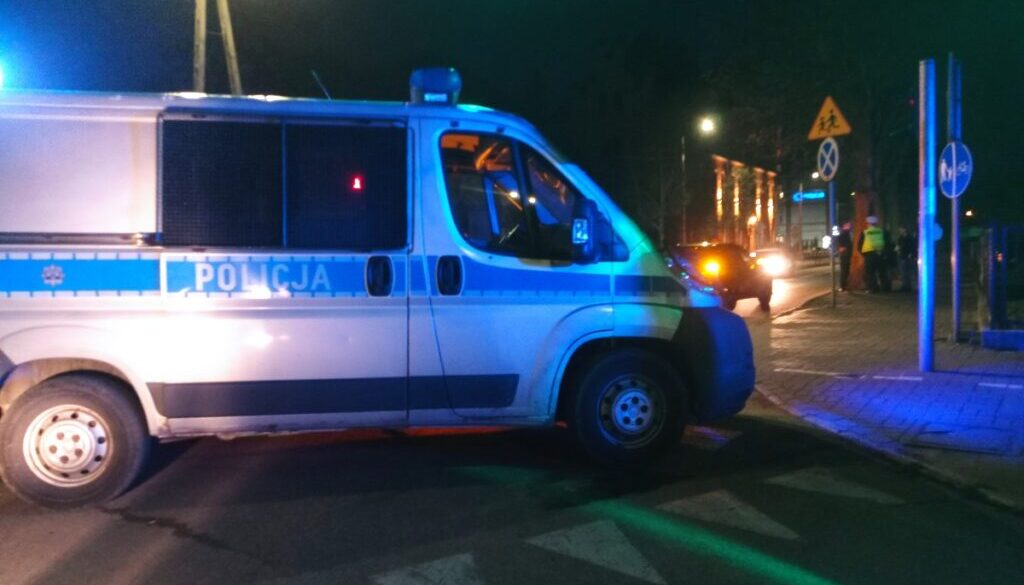 Policyjny radiowóz na przejściu dla pieszych w nocy